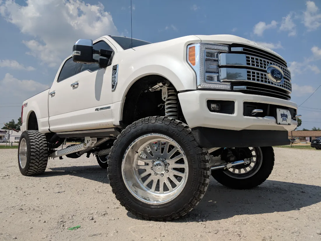 Lifted white Ford Super Duty on polished wheels and 40 inch mud-terrain tires